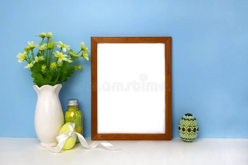 Decoración de Pascua con la maqueta en blanco del marco en la pared azul foto de archivo libre de regalías Decoración de Pascua con la maqueta en blanco del marco en la pared azul foto de archivo libre de regalías