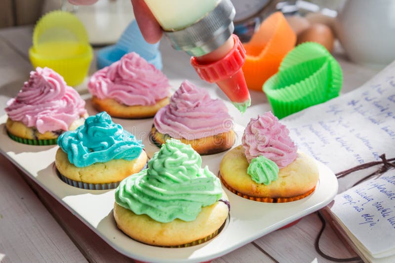 Decorar muffins deliciosos com creme e decoração imagens de stock