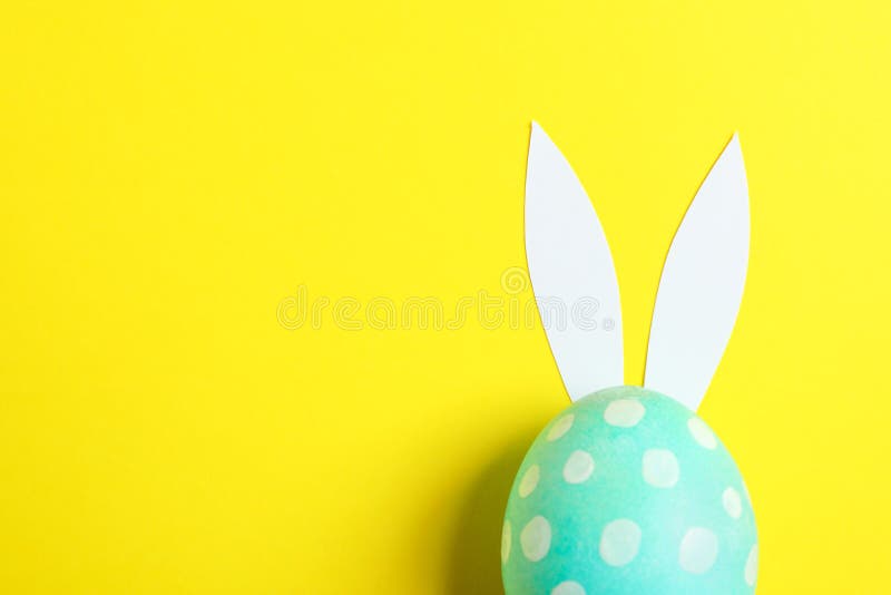 Decorated Easter egg with cute bunnies ears on yellow background stock photography Decorated Easter egg with cute bunnies ears on yellow background stock photography