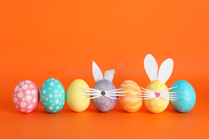 Decorated Easter eggs and cute bunny`s ears on color background