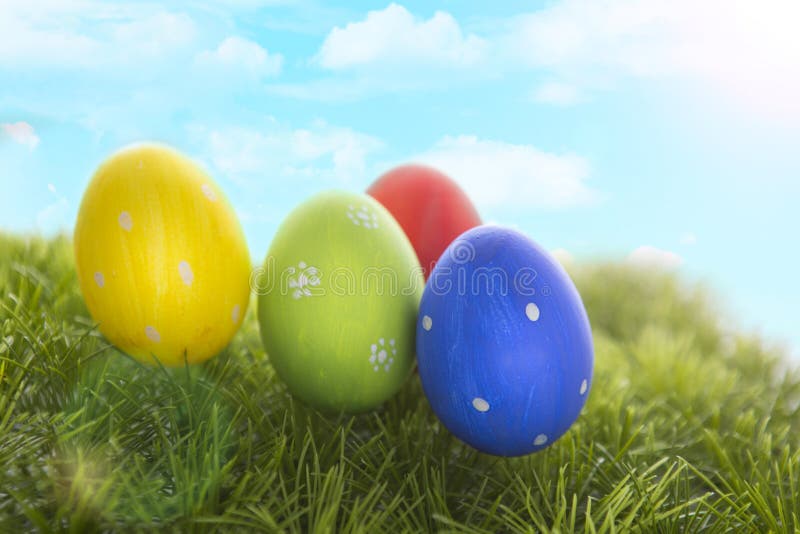 Decorated easter eggs in grass on sky background stock photos