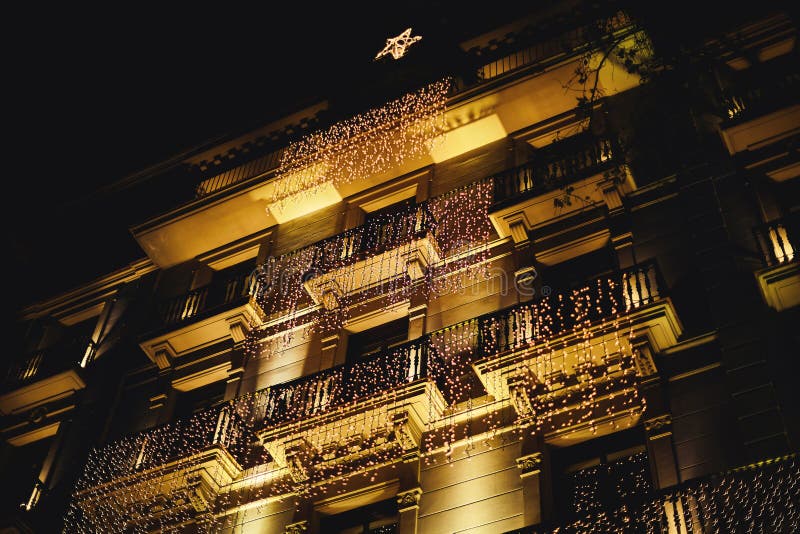 Decorated house with christmas lights. many garlands hung on the balconies of the historic building in Barcelona in the form of a