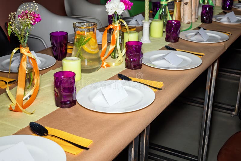 Decorated table in mexican style ready for dinner. Beautifully decorated colorful table set with flowers, candles, plates and serv