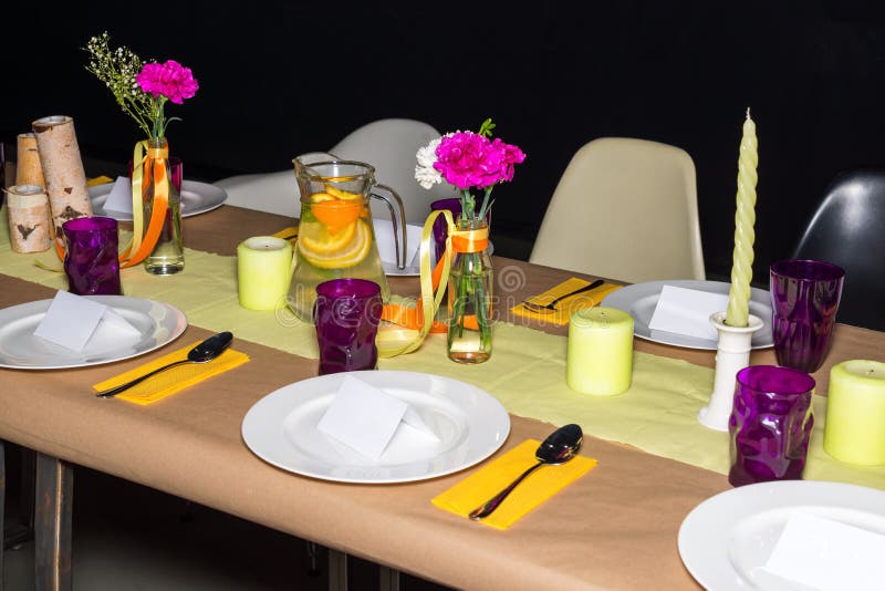 Decorated table in mexican style ready for dinner. Beautifully decorated colorful table set with flowers, candles, plates and serv