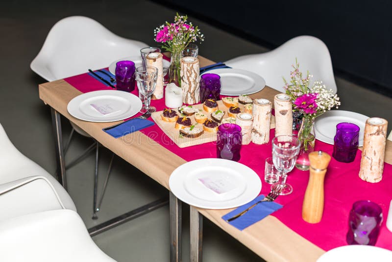 Decorated table ready for dinner. Beautifully decorated table set with flowers, candles, plates and serviettes for wedding or anot