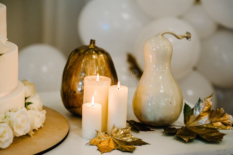 Decorated table for wedding. White balloons, candles, autumn leaves and small pumpkins. Autumn location and Halloween decor. Setting.