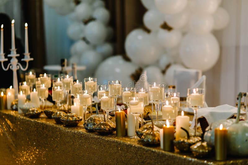 Decorated table for wedding. White balloons, candles, autumn leaves and small pumpkins. Autumn location and Halloween decor. Setting.