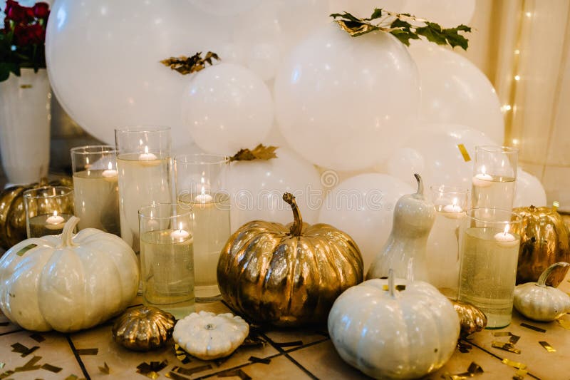 Decorated table for wedding. White balloons, candles, autumn leaves and small pumpkins. Autumn location and Halloween decor. Setting.