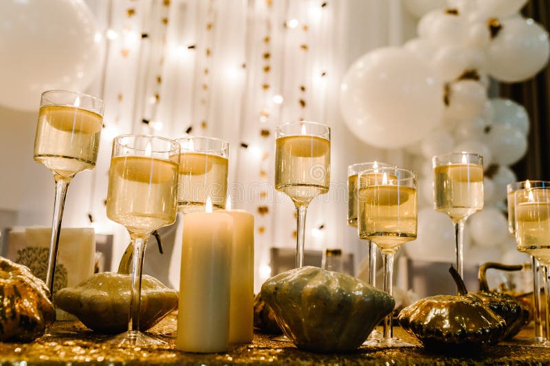 Decorated table for wedding. White balloons, candles, autumn leaves, and small pumpkins. Autumn location and Halloween decor. Setting