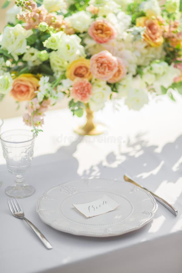 Decorated wedding table with beautiful flower composition, glass and plate,word bride, outdoor, fine art.