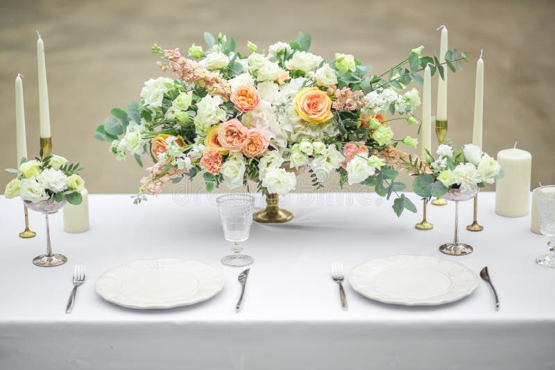 Decorated wedding table for two with beautiful flower composition of flowers, glasses for wine and plates, outdoor, fine