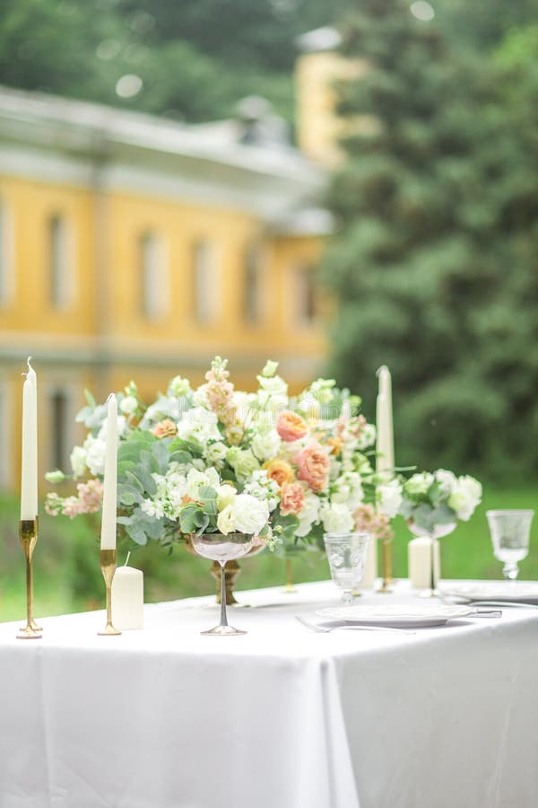 Decorated wedding table for two with beautiful flower composition, glasses for wine, candles and plates, outdoor, fine