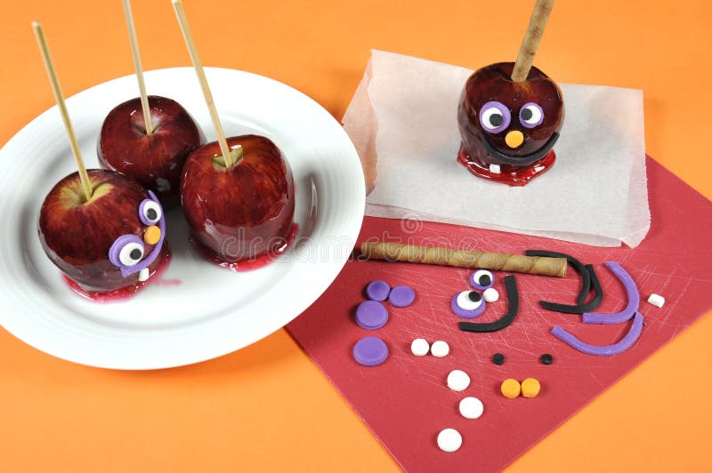 Decorating red toffee apples with funny crazy smiling faces for Halloween stock photography