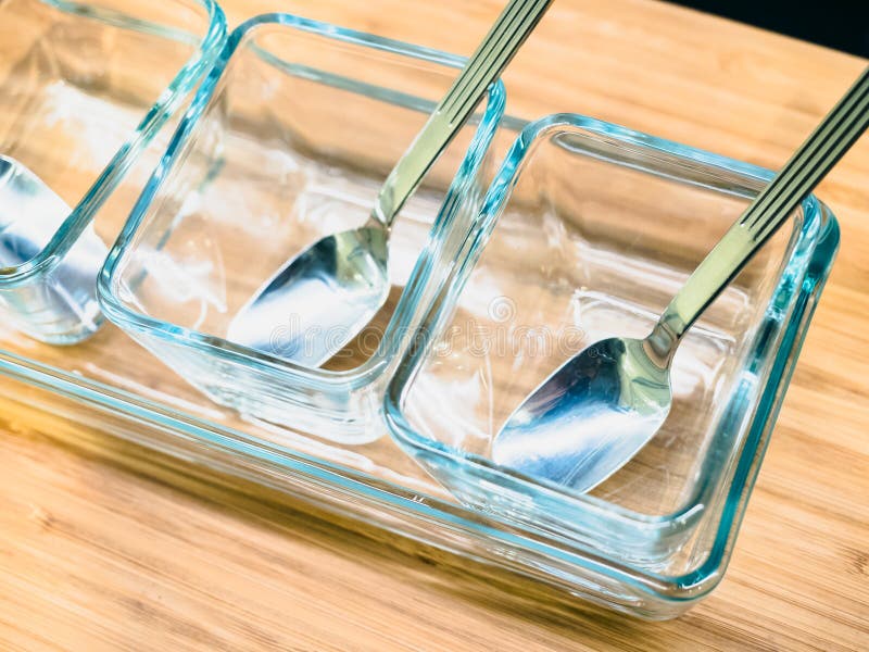 Decoration from shiny silver spoon in glass bowl with background wooden table