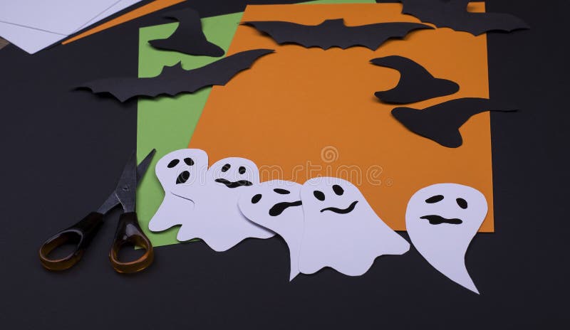 Halloween party handcraft paper card of laughing flying ghosts, spirits, black bats on a black background.
