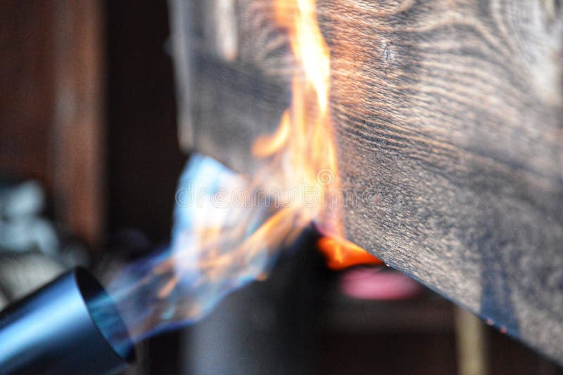 Blowtorch flames on a piece of wood showing shou sugi ban technique.