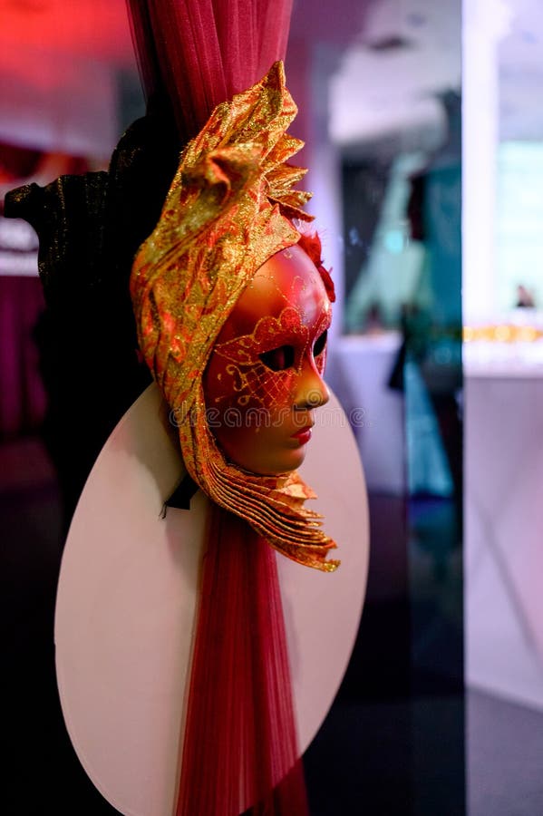 A decorative element for a masquerade or carnival with a side profile of a mask. Venetian masquerade mask in gold and red tones on a vertical stand. Side profile mask stock images, royalty-free photos and pictures
