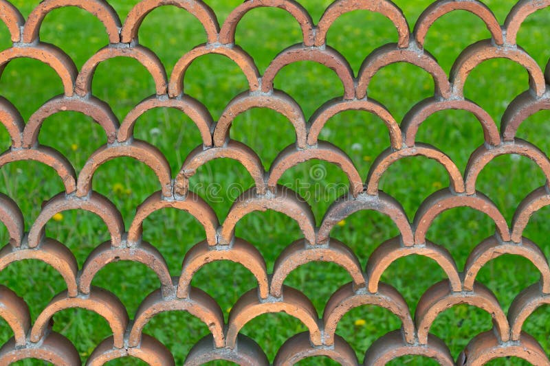 Decorative fence made of semicircular bricks, arranged in a staggered pattern, creating a unique design with gaps between the royalty free stock photography