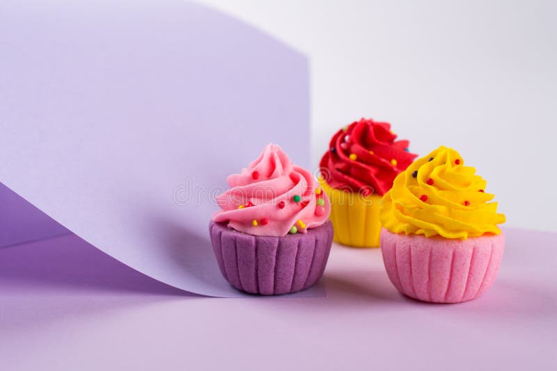Decorative multicolored sugar cupcakes on light purple background royalty free stock photography