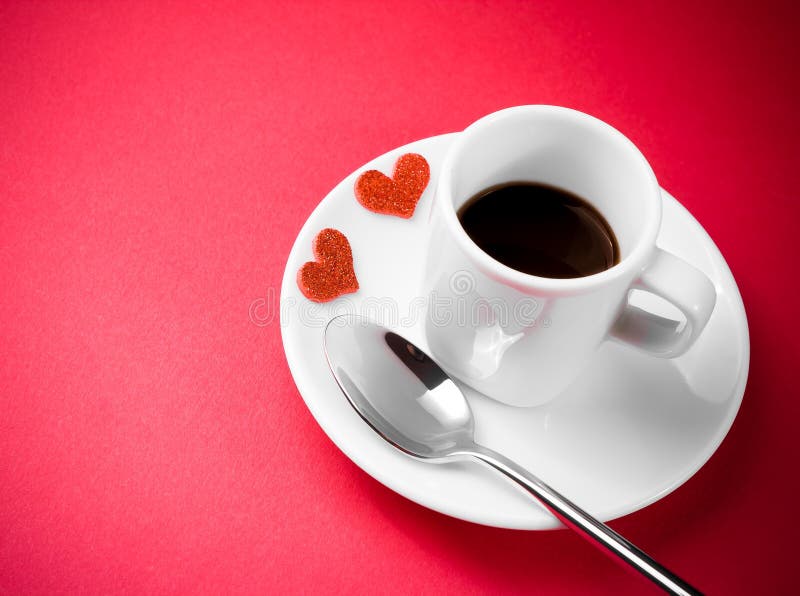 Decorative red hearts near cup of coffee on red table, concept valentine day