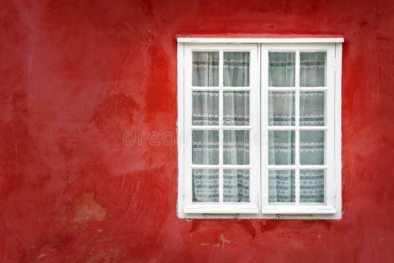 Decorative window on an old red stucco wall