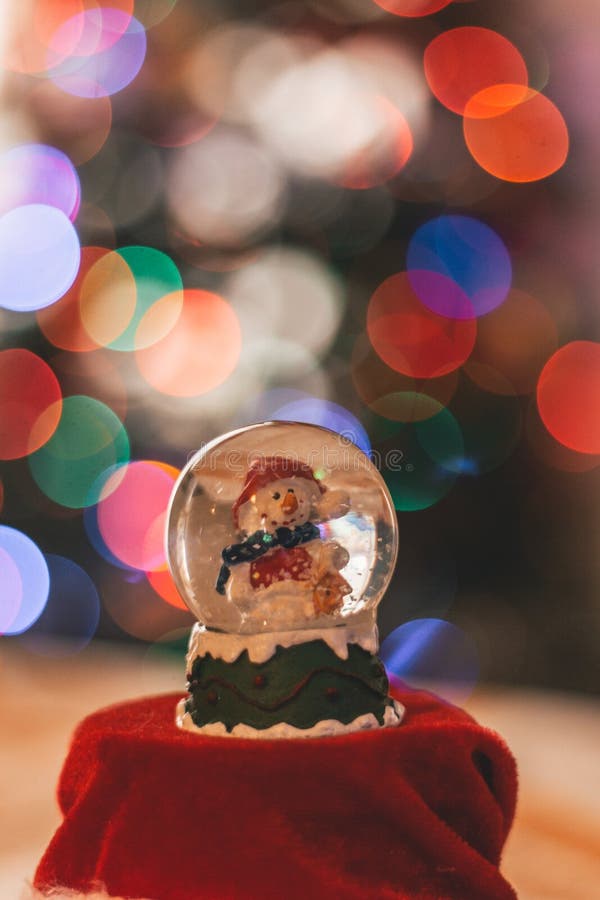 Decorazione della palla di vetro del pupazzo di neve con le luci di Natale nei precedenti fotografia stock Decorazione della palla di vetro del pupazzo di neve con le luci di Natale nei precedenti fotografia stock