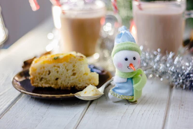 Christmas decoration at white table - snowman with piece of pie in spoon. Christmas decoration at white table - snowman with piece of pie in spoon