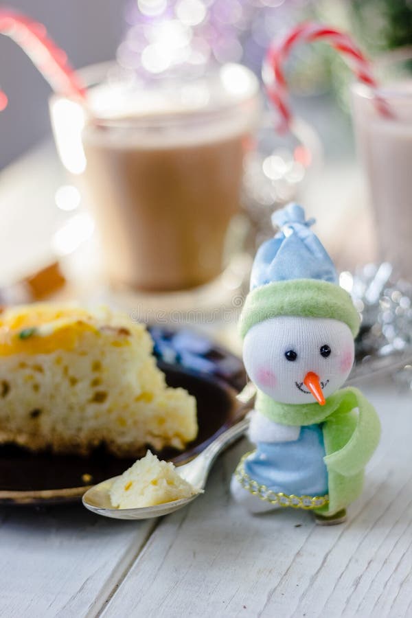 Christmas decoration at white table - snowman with piece of pie in spoon. Christmas decoration at white table - snowman with piece of pie in spoon