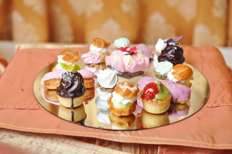 Decorazione di nozze con i bigné, le meringhe ed i muffin colorati Disposizione elegante e lussuosa di evento con i dolci variopi immagine stock Decorazione di nozze con i bigné, le meringhe ed i muffin colorati Disposizione elegante e lussuosa di evento con i dolci variopi immagine stock