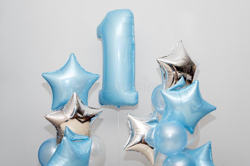 Decorazione per 1 anno di compleanno, anniversario Mazzo di palloni e di stelle blu a forma di gel su fondo leggero Simbolo di fotografia stock Decorazione per 1 anno di compleanno, anniversario Mazzo di palloni e di stelle blu a forma di gel su fondo leggero Simbolo di fotografia stock