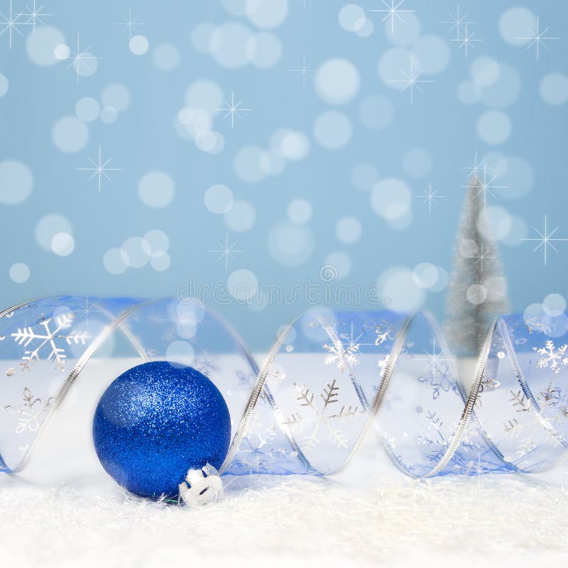 Decoração com uma bola azul, fita curvada do Natal em vagabundos do bokeh imagens de stock Decoração com uma bola azul, fita curvada do Natal em vagabundos do bokeh imagens de stock