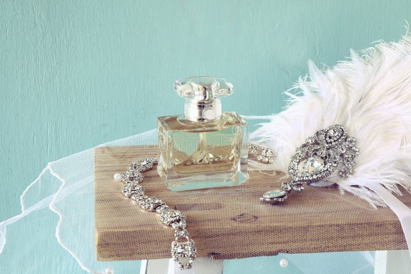 Image of gatsby style diamond head decoration with feathers next to perfume bottle on toilet table. Vintage filtered. Image of gatsby style diamond head decoration with feathers next to perfume bottle on toilet table. Vintage filtered