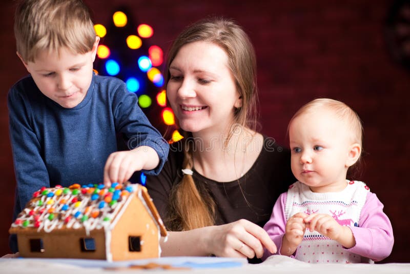 Family decorating gingerbread house on Christmas eve. Family decorating gingerbread house on Christmas eve