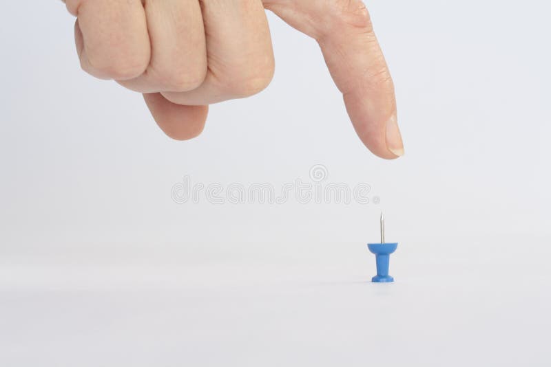 Finger about to press down on blue push pin. Finger about to press down on blue push pin