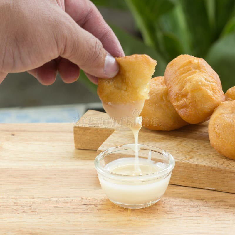 Deep Fried Dough Bun Dip in Sweetened Condensed Milk Stock Photo