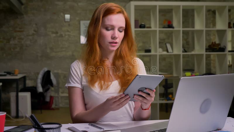 Deeplu a concentré le gingembre la femelle que caucasienne frappe à toute volée son comprimé tout en reposant le froid à son bure banque de vidéos