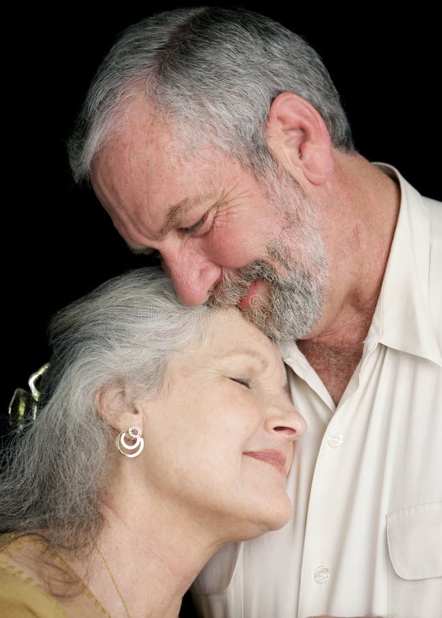 A beautiful middle aged couple tenderly embracing eachother. They are very much in love. Black background. Happy embracing couple stock images, royalty-free photos and pictures