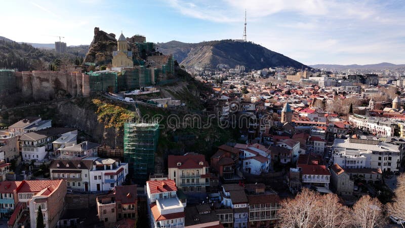 Historical Narikala Fortress and St. Nicholas Church overlooking traditional red-roofed houses in ancient Tbilisi city.