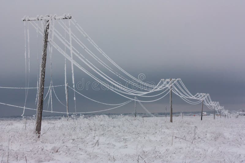 Broken phase electrical power lines with hoarfrost on the wooden electric poles on countryside in the winter, pole with wires. Broken phase electrical power lines with hoarfrost on the wooden electric poles on countryside in the winter, pole with wires