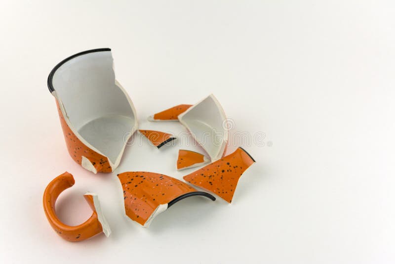 Defekter orange Becher auf wei?em Hintergrund Zahlreiche St?cke der Schale lizenzfreie stockfotos Defekter orange Becher auf wei?em Hintergrund Zahlreiche St?cke der Schale lizenzfreie stockfotos