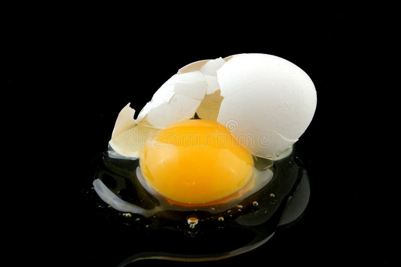 Broken egg with white eggshell and yolk spilling out on black background. Broken egg with white eggshell and yolk spilling out on black background.