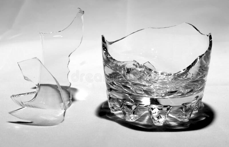 A broken whiskey glass with splinters stands on a white background. A broken whiskey glass with splinters stands on a white background.