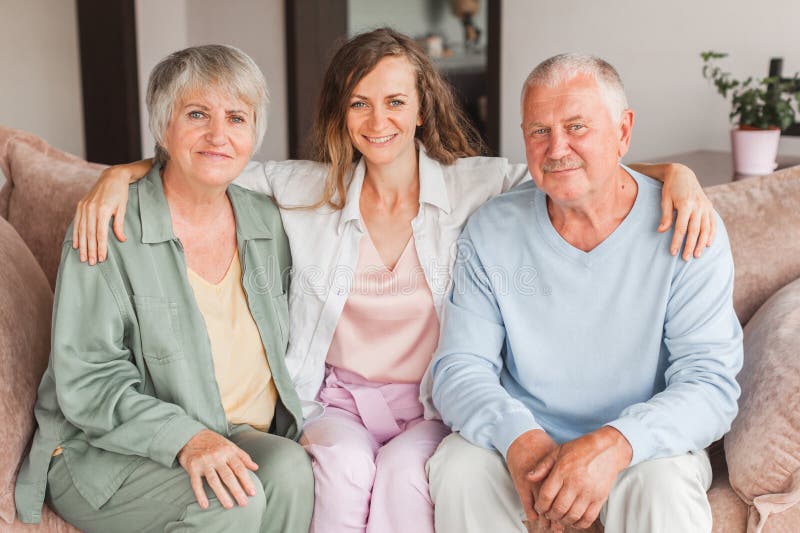 Portrait overjoyed attractive young woman having fun with happy older parents. Laughing two generations enjoying free leisure family time together at home, posing for photo. Portrait overjoyed attractive young woman having fun with happy older parents. Laughing two generations enjoying free leisure family time together at home, posing for photo