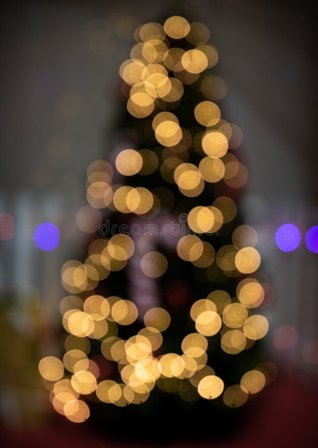 Defocused Christmas tree with bokeh fairy lights glowing. Abstract blur of christmas tree shape. Defocused Christmas tree with bokeh fairy lights glowing. Abstract blur of christmas tree shape