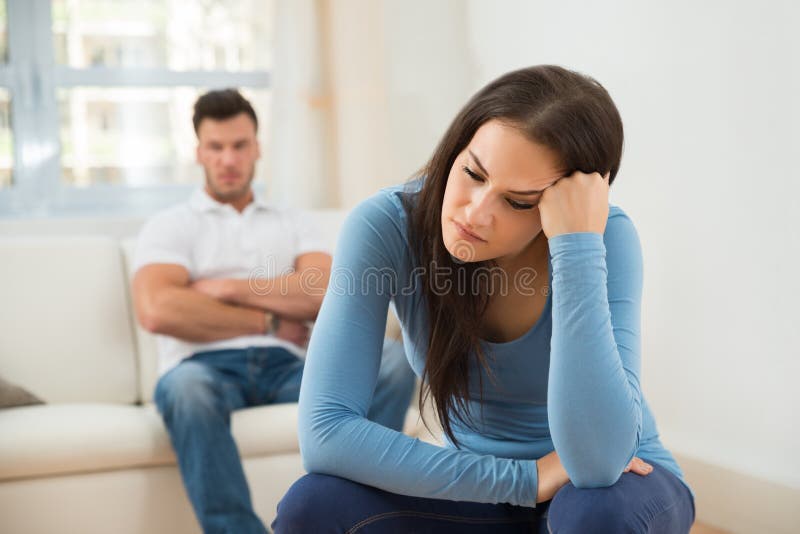 Defocused man in front of sad young woman stock photos