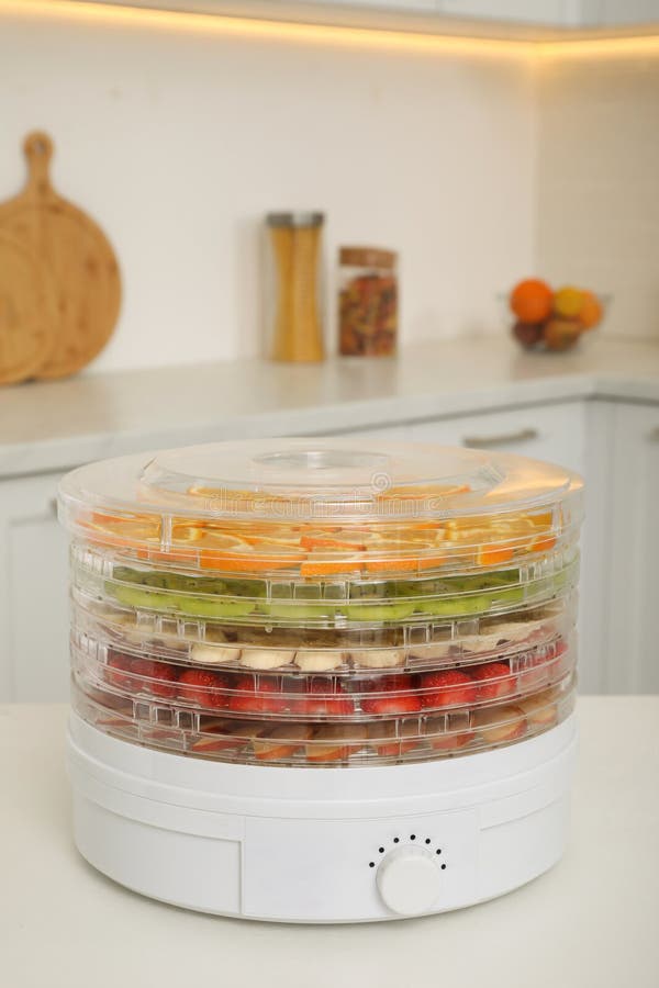 Dehydrator Machine with Fruits and Berries on White Table in Kitchen