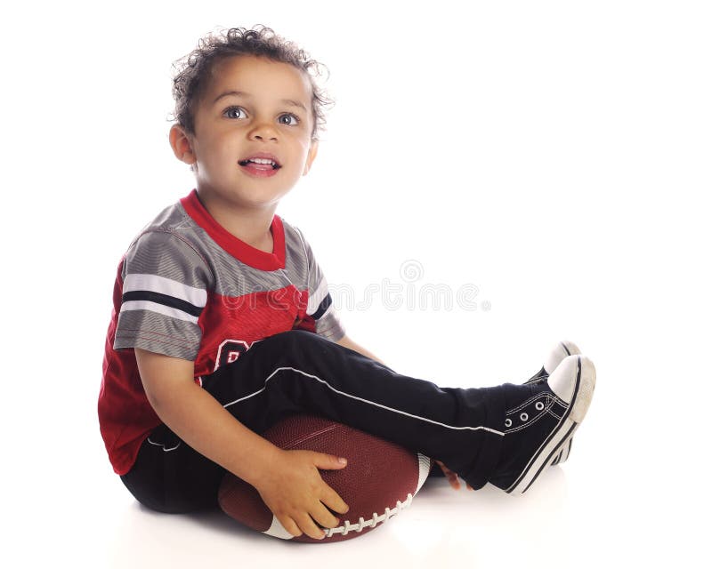 An adorable preschooler happily looking up while holding his football. On a white background. An adorable preschooler happily looking up while holding his football. On a white background.