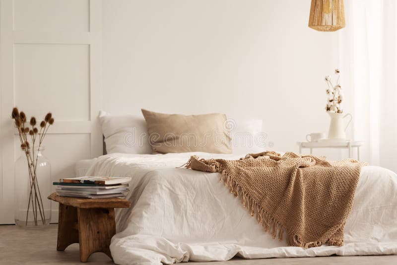 Deken op wit bed in natuurlijk slaapkamerbinnenland met installaties en houten kruk royalty-vrije stock afbeelding Deken op wit bed in natuurlijk slaapkamerbinnenland met installaties en houten kruk royalty-vrije stock afbeelding