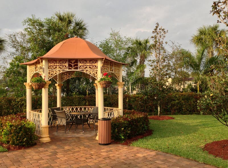 Decorative gazebo with an orange shaped roof in a landscaped garden.