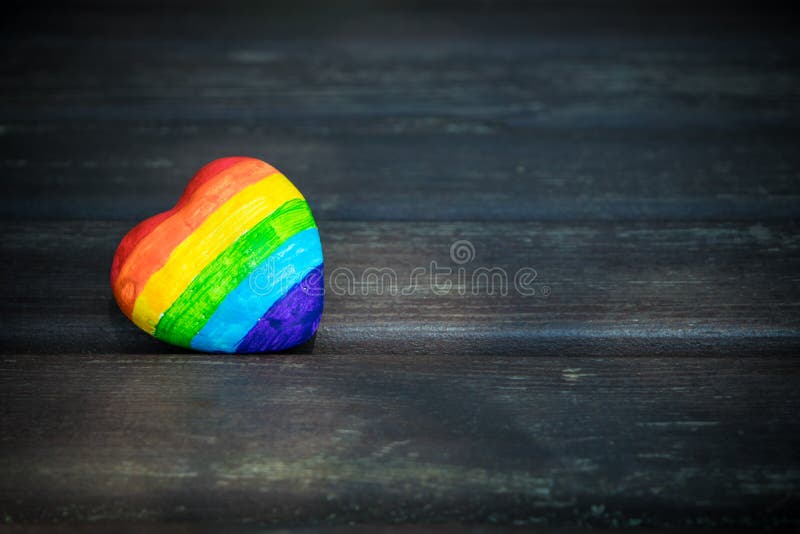Dekorativ hjärta med regnbågeband på mörk träbakgrund LGBT-stolthetflagga, symbol av lesbiskt, glat som är bisexuell, transgender